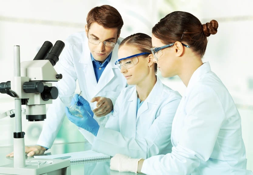 3 scientists using a petri dish and a microscope 