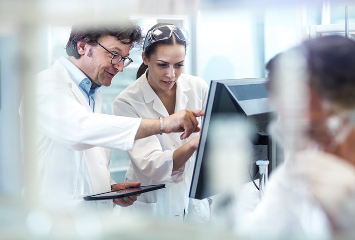 2 scientists working on a computer and using an ipad tablet 