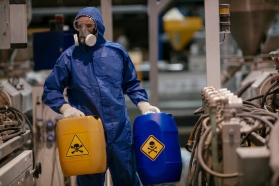 factory worker in hazmat suit moving harmful chemicals