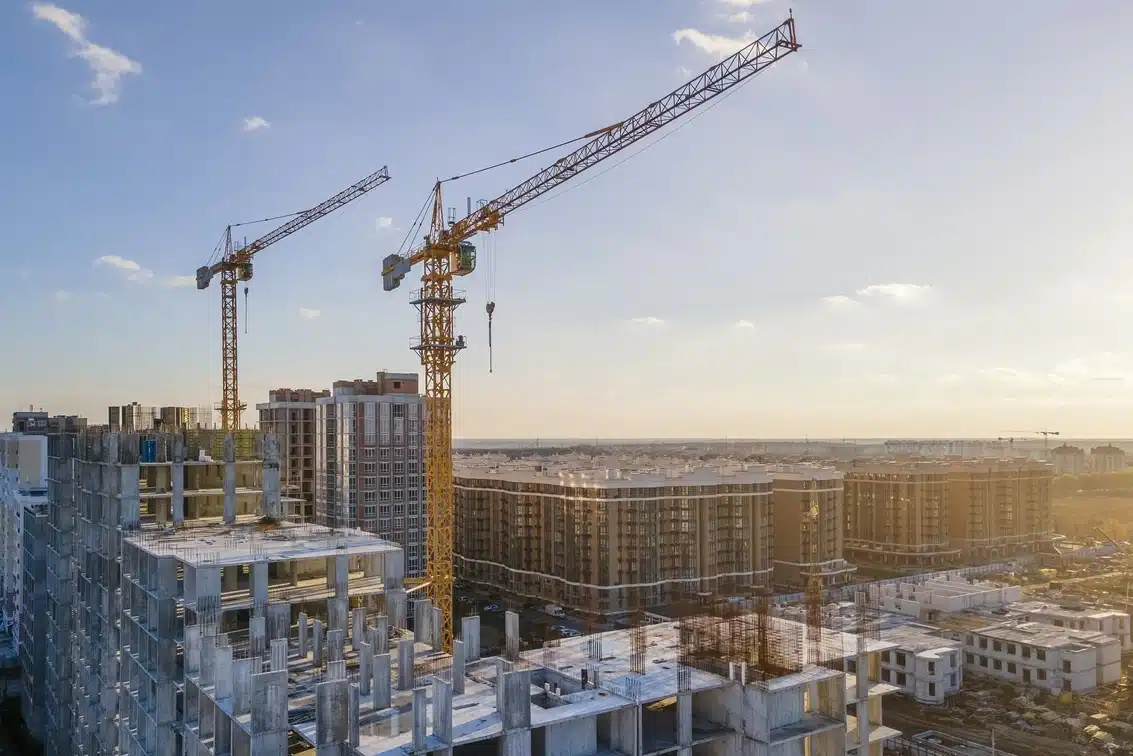 Cranes on the construction site surrounded by new real estates.