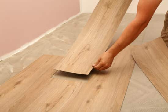 Work on laying flooring. Worker installing new vinyl tile floor.