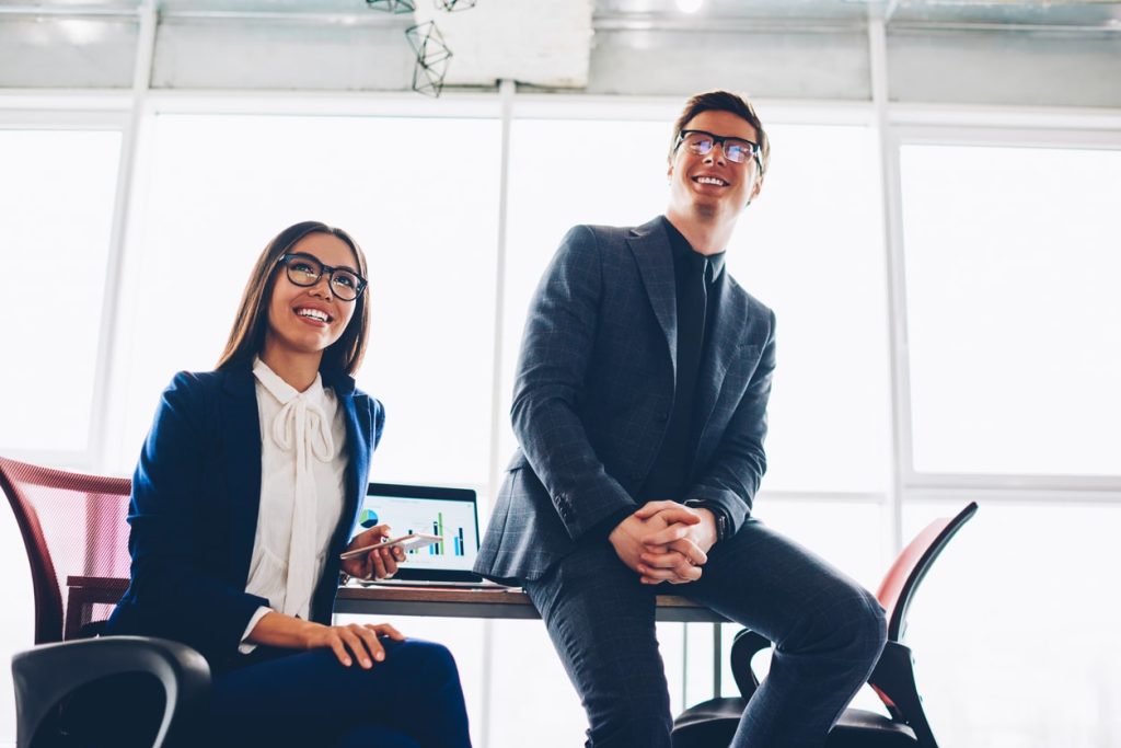 Prosperous business colleagues in formal wear sitting in office during meeting satisfied with company achievements, successful male and female finance partners happy about budget incomes and cooperation