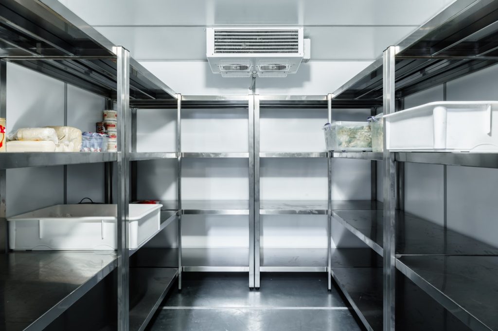 Refrigerator chamber with steel shelves in a restaurant close up